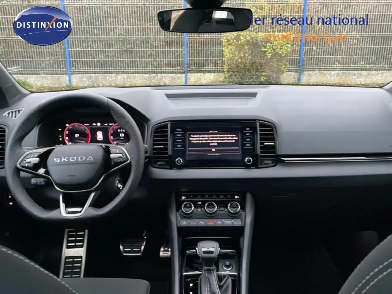 Vue intérieure frontale du tableau de bord noir du Skoda Karoq 2025 avec volant multifonction et écran central tactile.