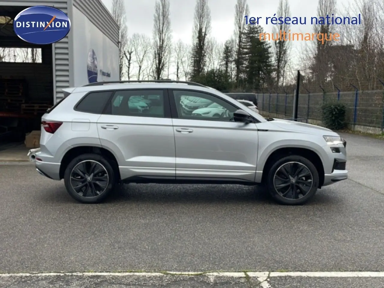 Vue profil droit d’un Skoda Karoq 1.5 TSI 150ch gris argent métallisé avec jantes noires biton sportline.