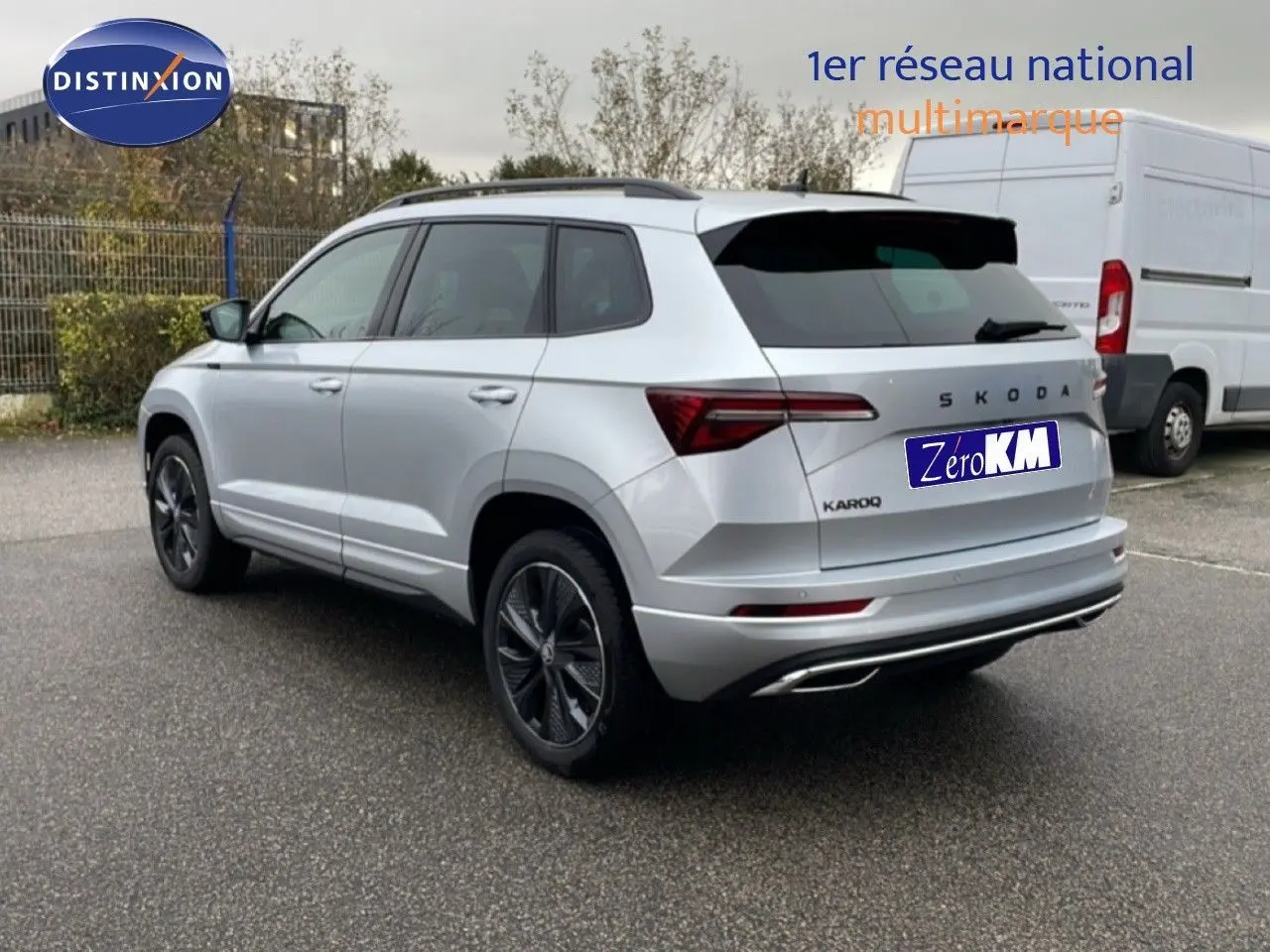 Vue 3/4 arrière droite d'un Skoda Karoq gris argent métallisé avec jantes noires et feux arrière LED distinctifs.