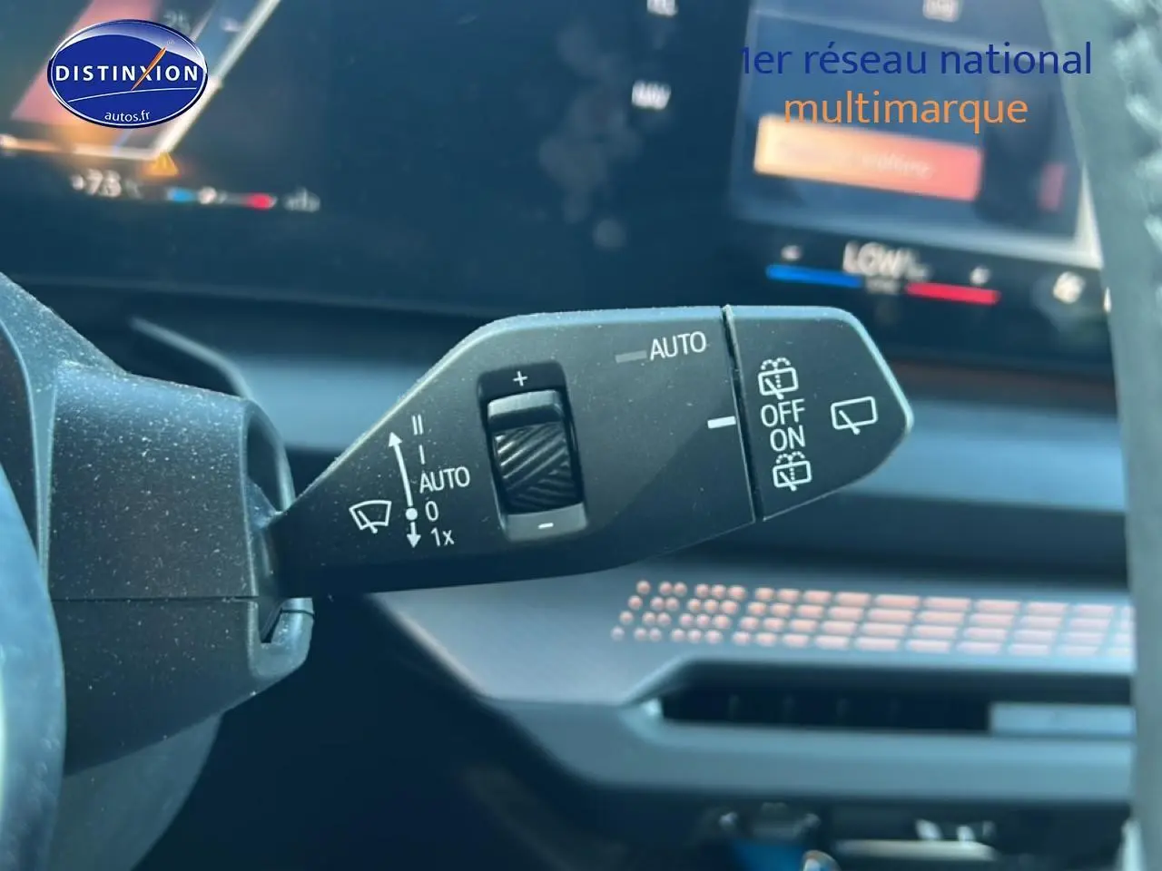 Gros plan sur la manette des essuie-glaces à gauche du volant dans l’habitacle d’une BMW Série 1 blanche.