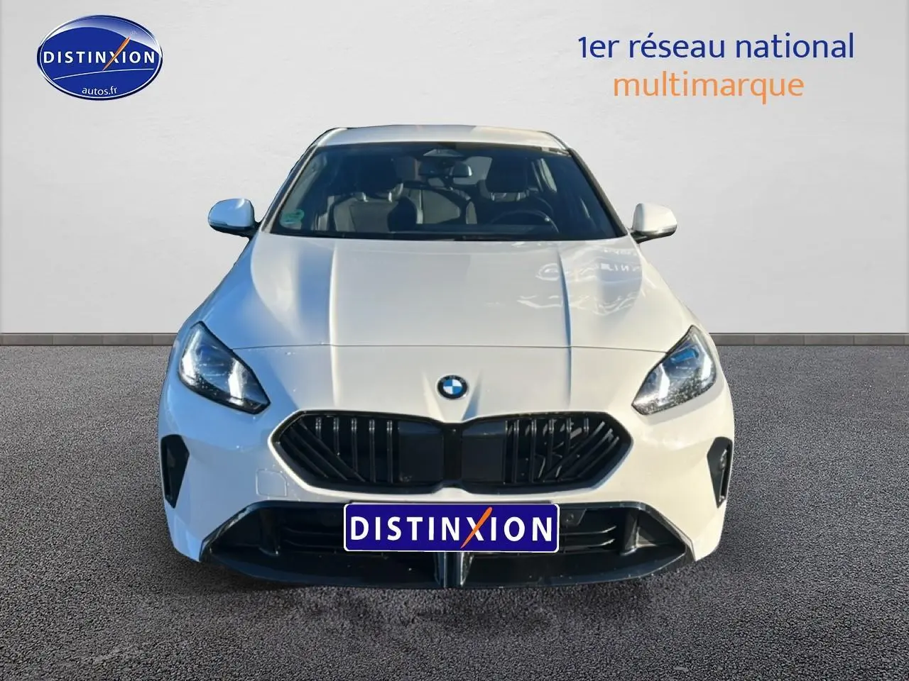 Vue frontale d'une BMW Série 1 blanche alpin avec calandre noire et phares LED allumés.