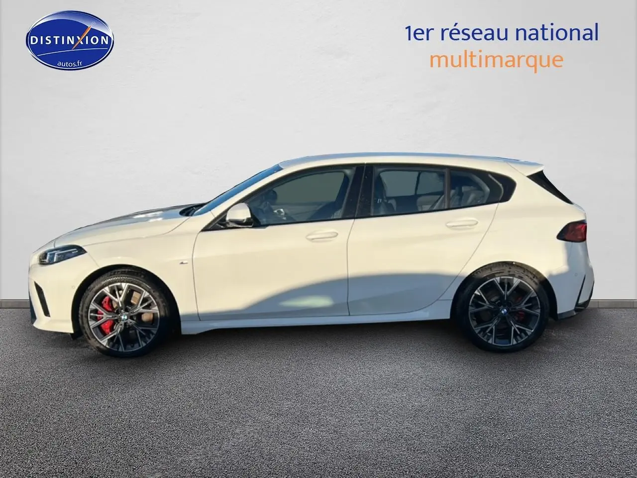 BMW Série 1 blanche alpin vue de profil côté gauche, avec jantes 18 pouces bicolores et étriers rouges.