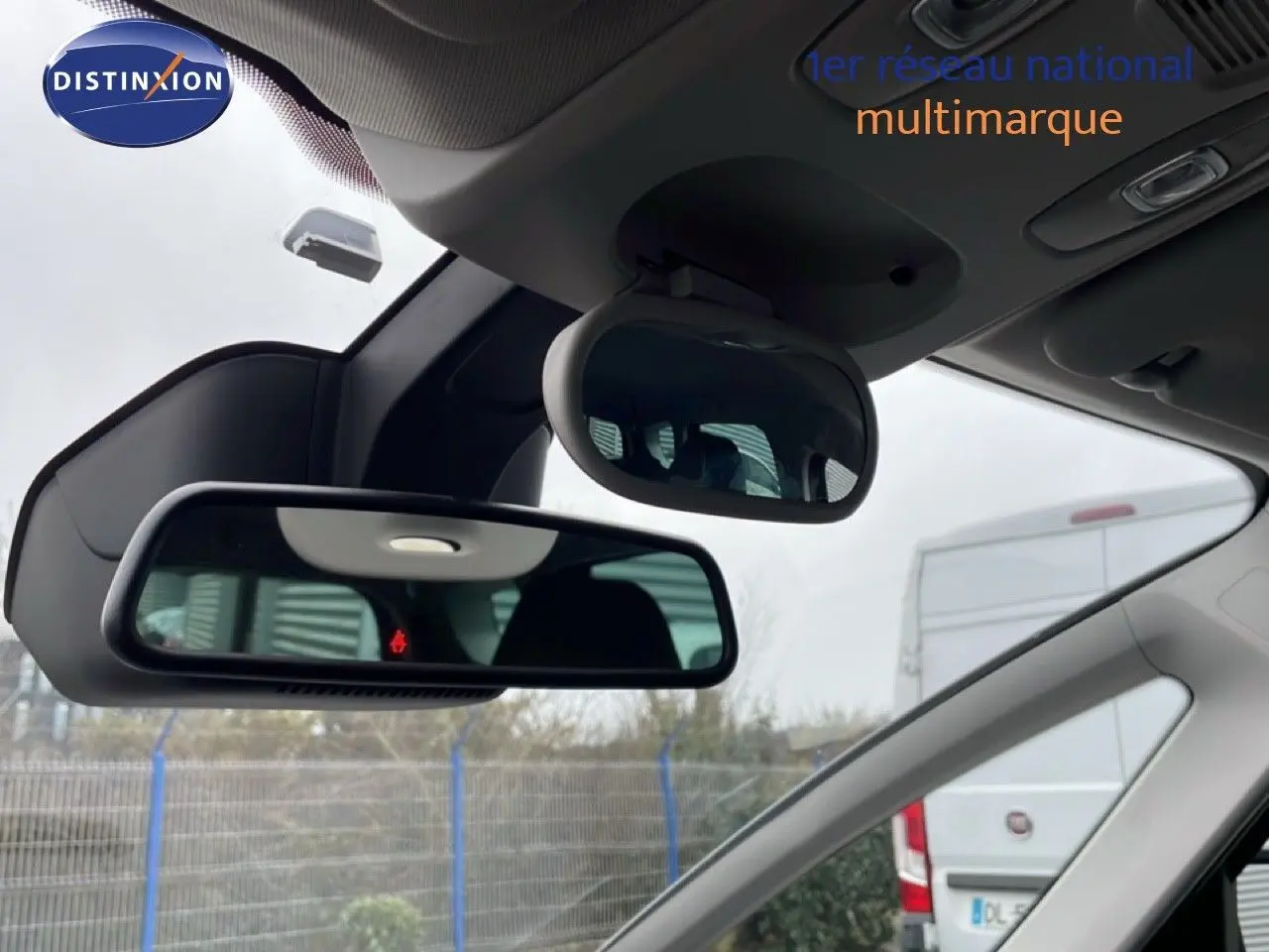 Vue intérieure du rétroviseur central et miroir enfant du Renault Grand Scenic noir étoile métal, avec arrière-plan extérieur flou.