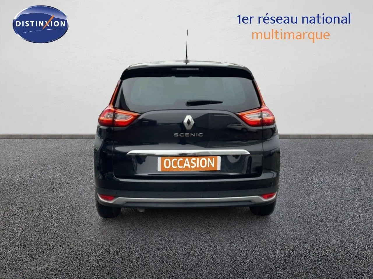 Vue arrière d’un Renault Grand Scenic noir étoile métal avec logo et feux arrière allumés sur fond neutre.