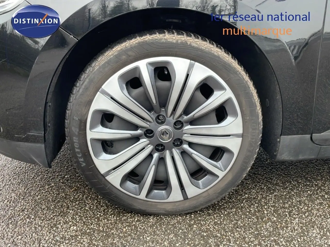 Gros plan sur la roue avant gauche du Renault Grand Scenic noir étoile métal, mettant en valeur la jante alu distinctive.