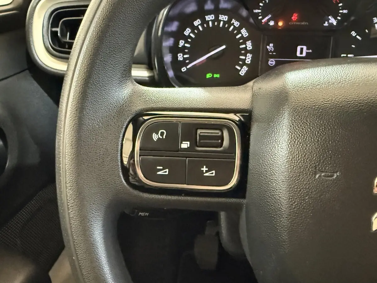 Gros plan sur le volant multifonctions noir de la Citroën C3 2021 avec commandes audio et tableau de bord en arrière-plan.