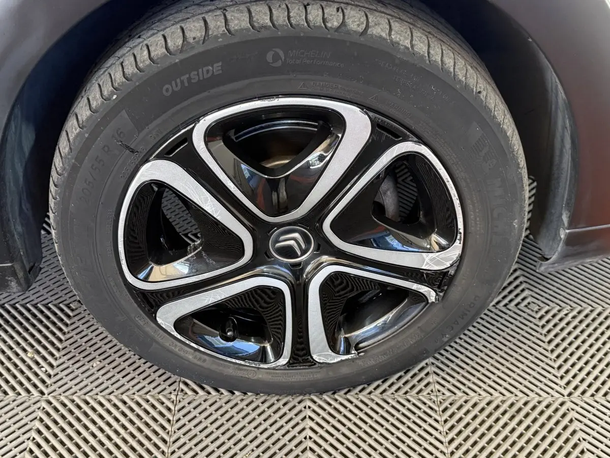 Gros plan sur la jante noire et argentée d'une Citroën C3 blanche, mettant en valeur le logo Citroën central.