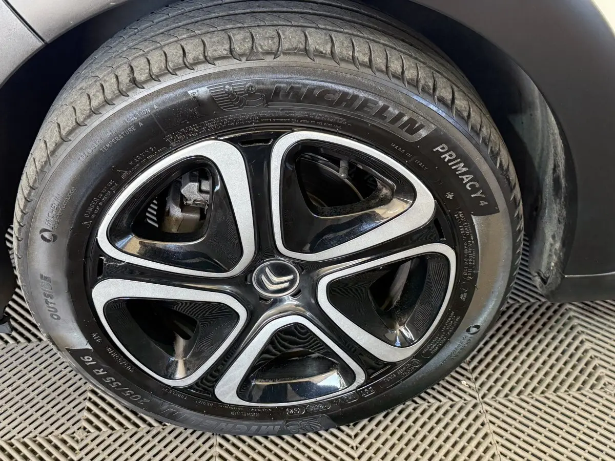 Gros plan sur la roue avant droite d'une Citroën C3 blanche, mettant en valeur la jante alliage noire et argentée.