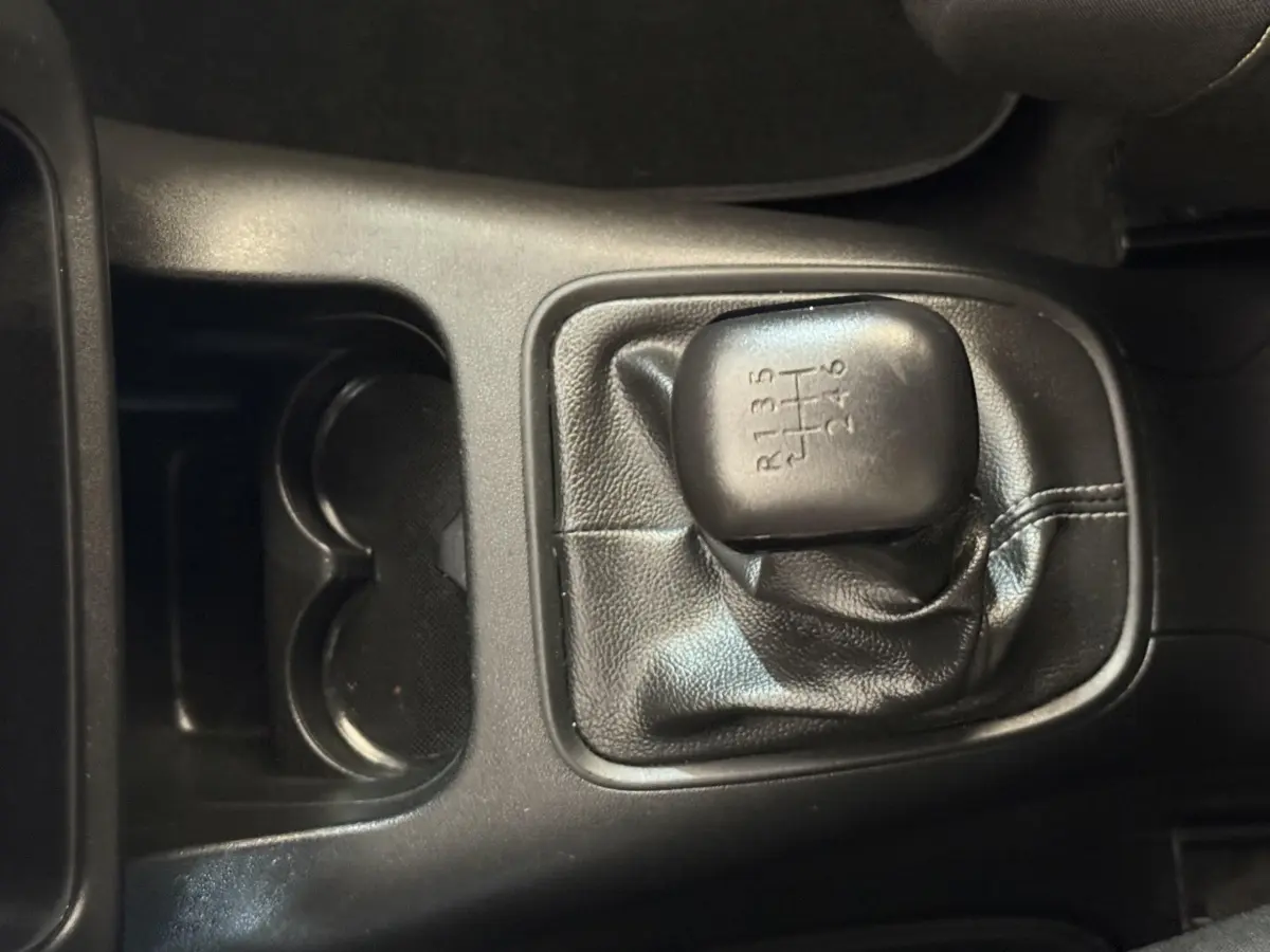 Gros plan sur le levier de vitesses manuel noir de la Citroën C3 BlueHDi 100 S&S BVM6 Feel blanche, intérieur sombre.