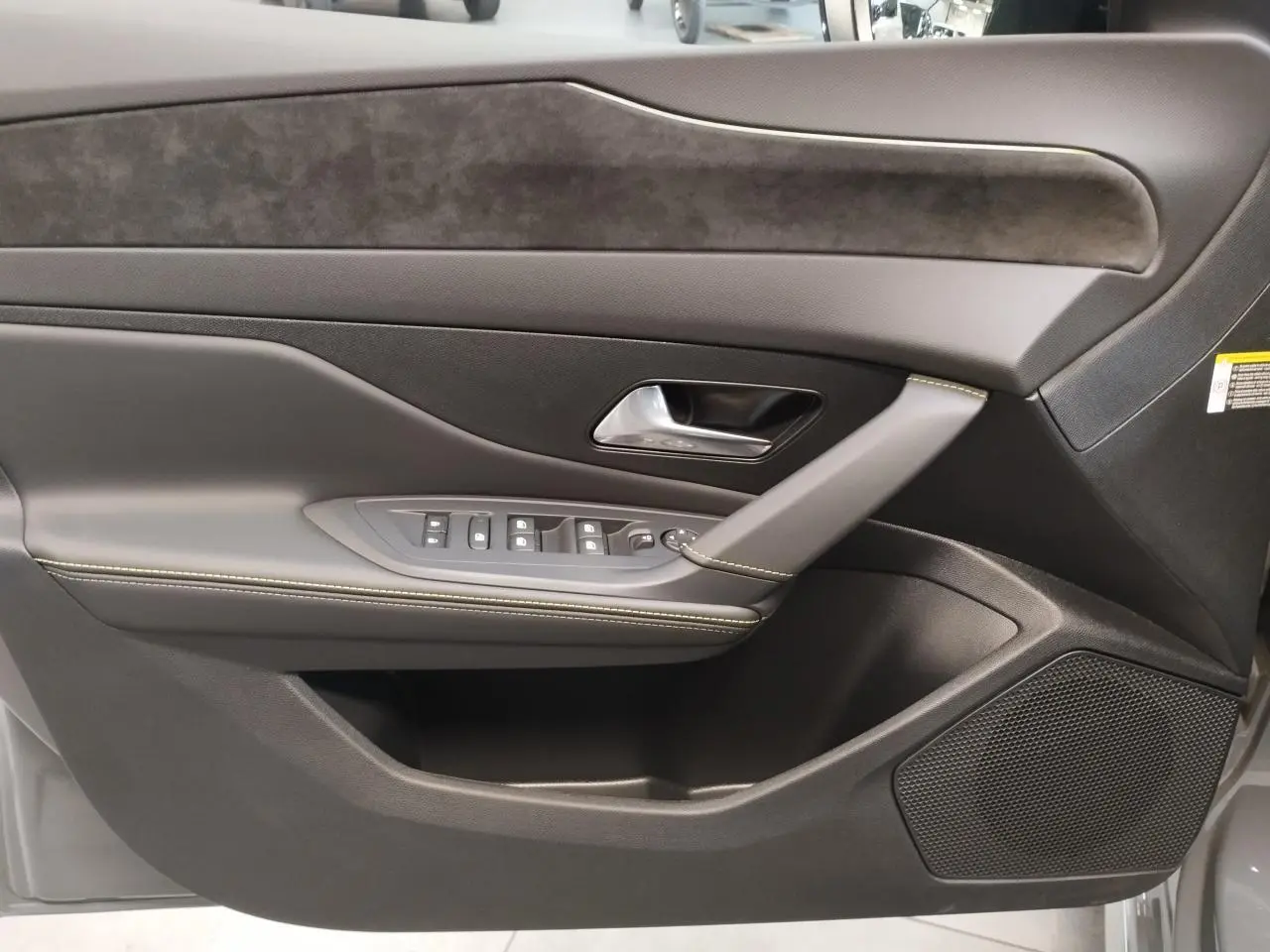 Détail de la porte avant gauche de la Peugeot 308 gris selenium, avec commandes de vitres et surpiqûres vert Adamite.