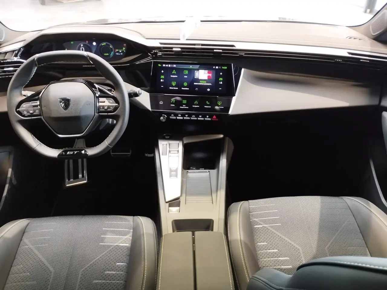 Vue intérieure avant de la Peugeot 308 Hybrid 2026, tableau de bord numérique et volant compact GT cuir noir.