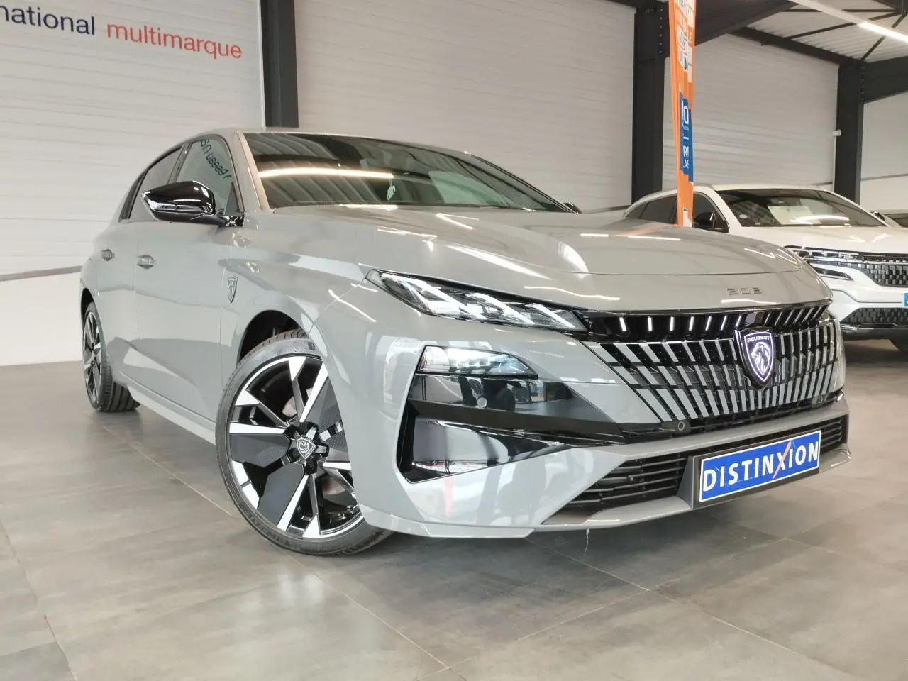 Peugeot 308 gris selenium vue 3/4 avant avec calandre noire et jantes alliage bi-ton distinctives.