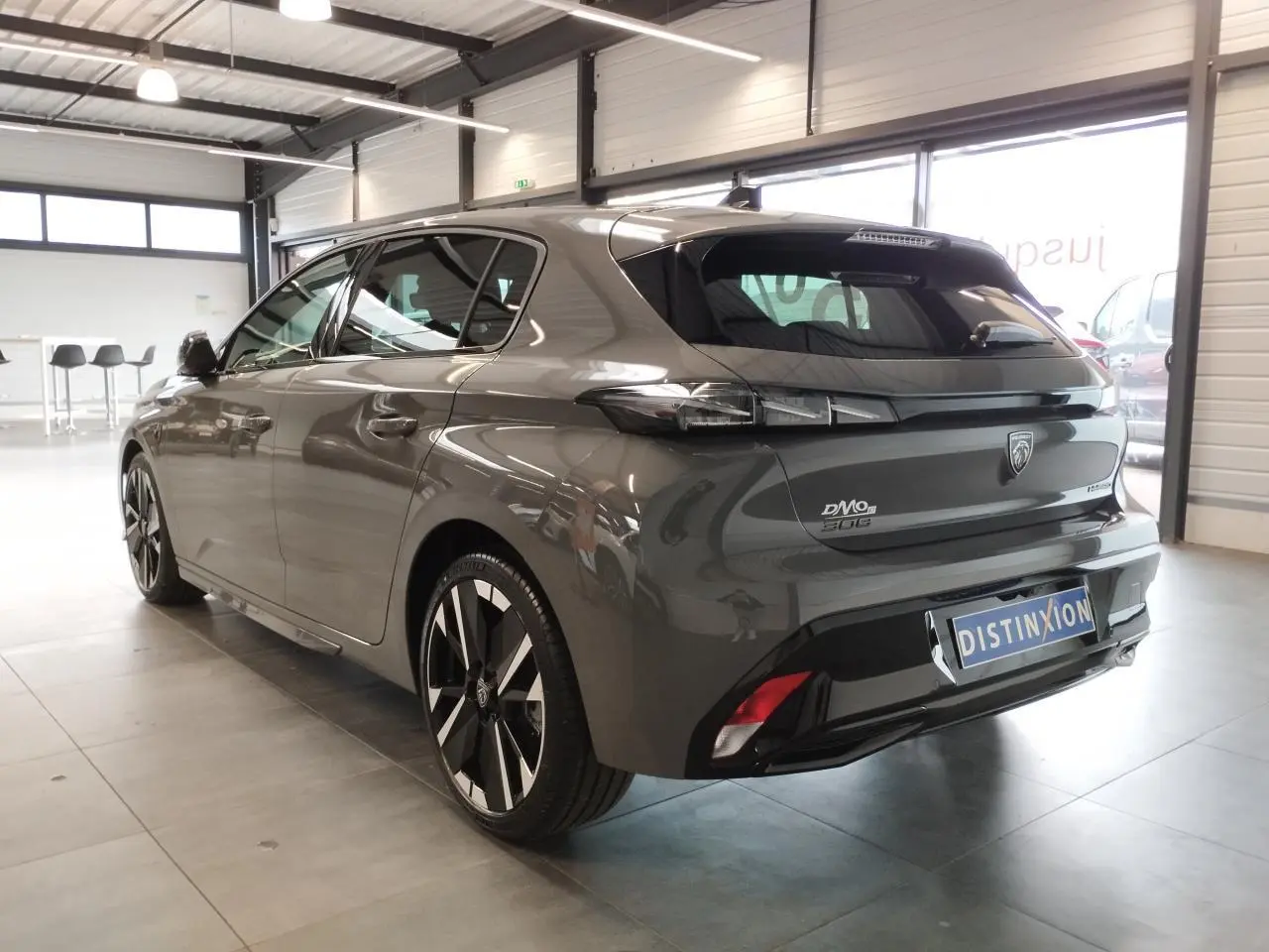 Vue 3/4 arrière droite d'une Peugeot 308 gris selenium avec jantes alliage bi-tons et feux arrière LED griffés.