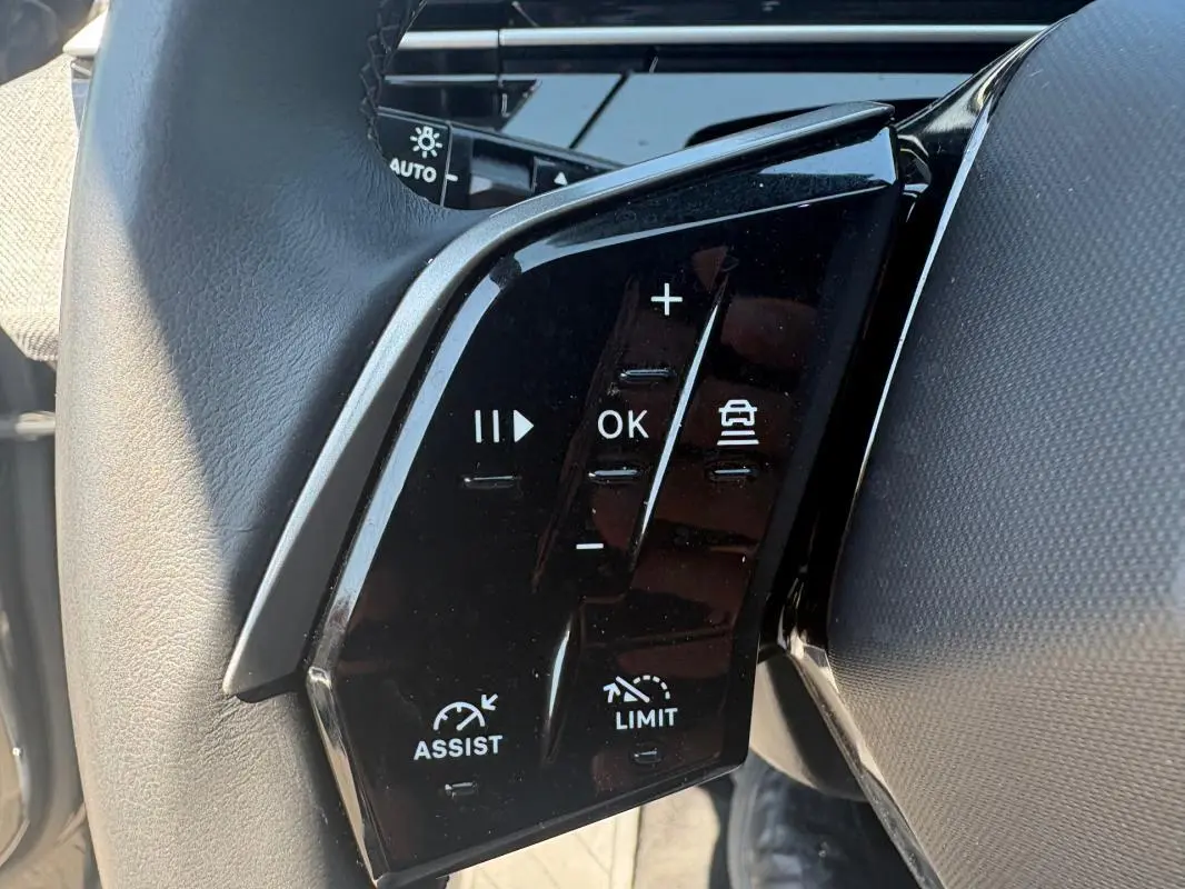 Gros plan sur les commandes noires au volant du Peugeot 3008 gris, version Hybrid 145 e-DCS6 Allure 2025.