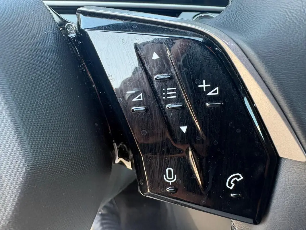 Gros plan sur les commandes vocales et audio au volant du Peugeot 3008 Hybrid gris, version 2025.