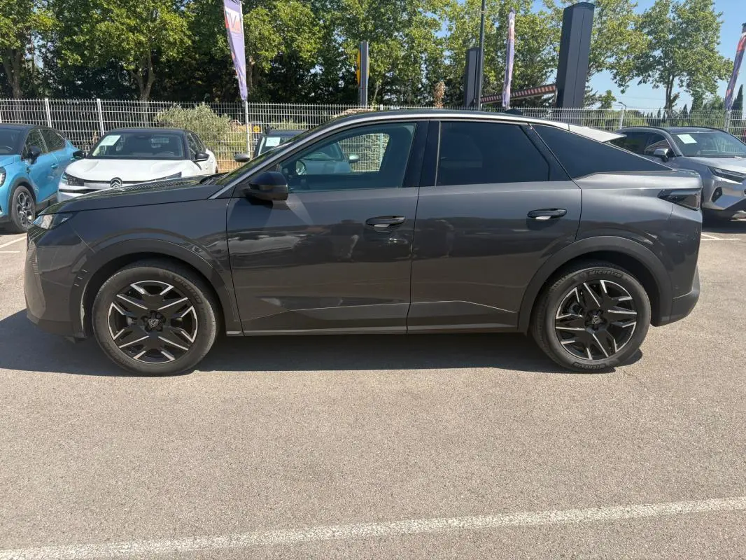 Vue de profil côté gauche d’un Peugeot 3008 Hybrid gris avec jantes alliage 18 pouces sur parking extérieur.