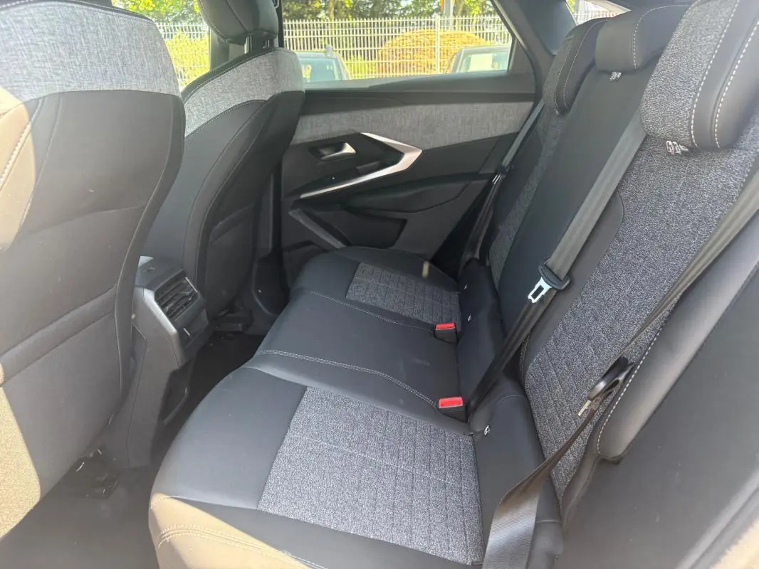 Vue intérieure côté droit des sièges arrière du Peugeot 3008 Hybrid 145 e-DCS6 Allure avec sellerie bi-matière grise et noire.