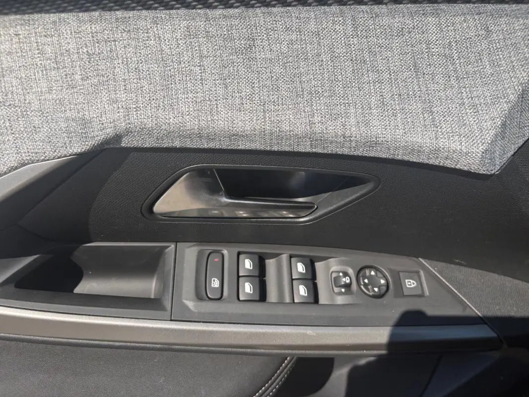 Vue du panneau de porte côté conducteur du Peugeot 3008 gris, avec commandes des vitres et rétroviseurs.