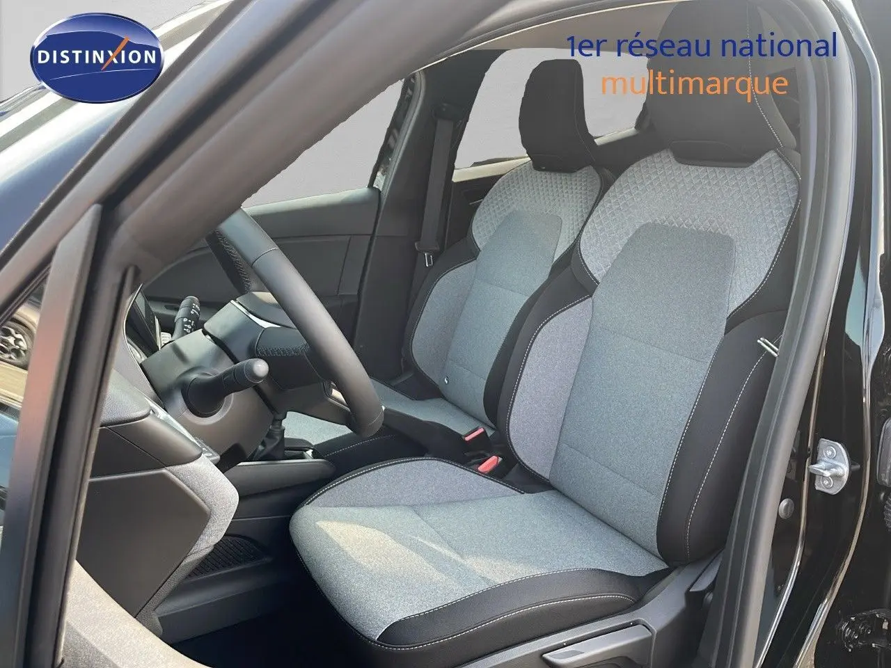 Intérieur de la Renault Clio 1.5 DCI 100ch Evolution 2025, sièges tissu gris clair et noir, vue côté conducteur porte ouverte.