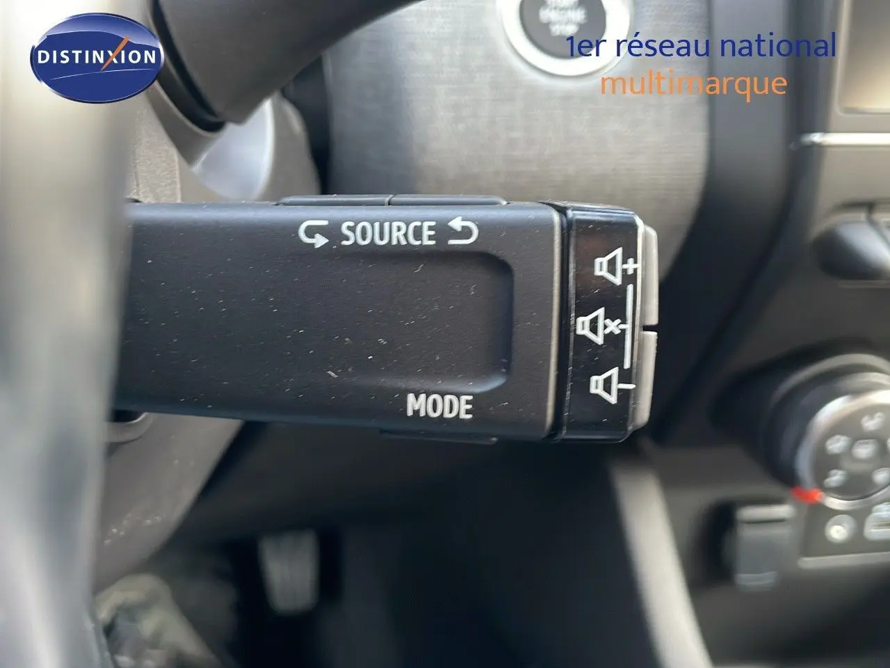 Gros plan sur la commande audio au volant d'une Renault Clio noire étoile métal, intérieur côté gauche.