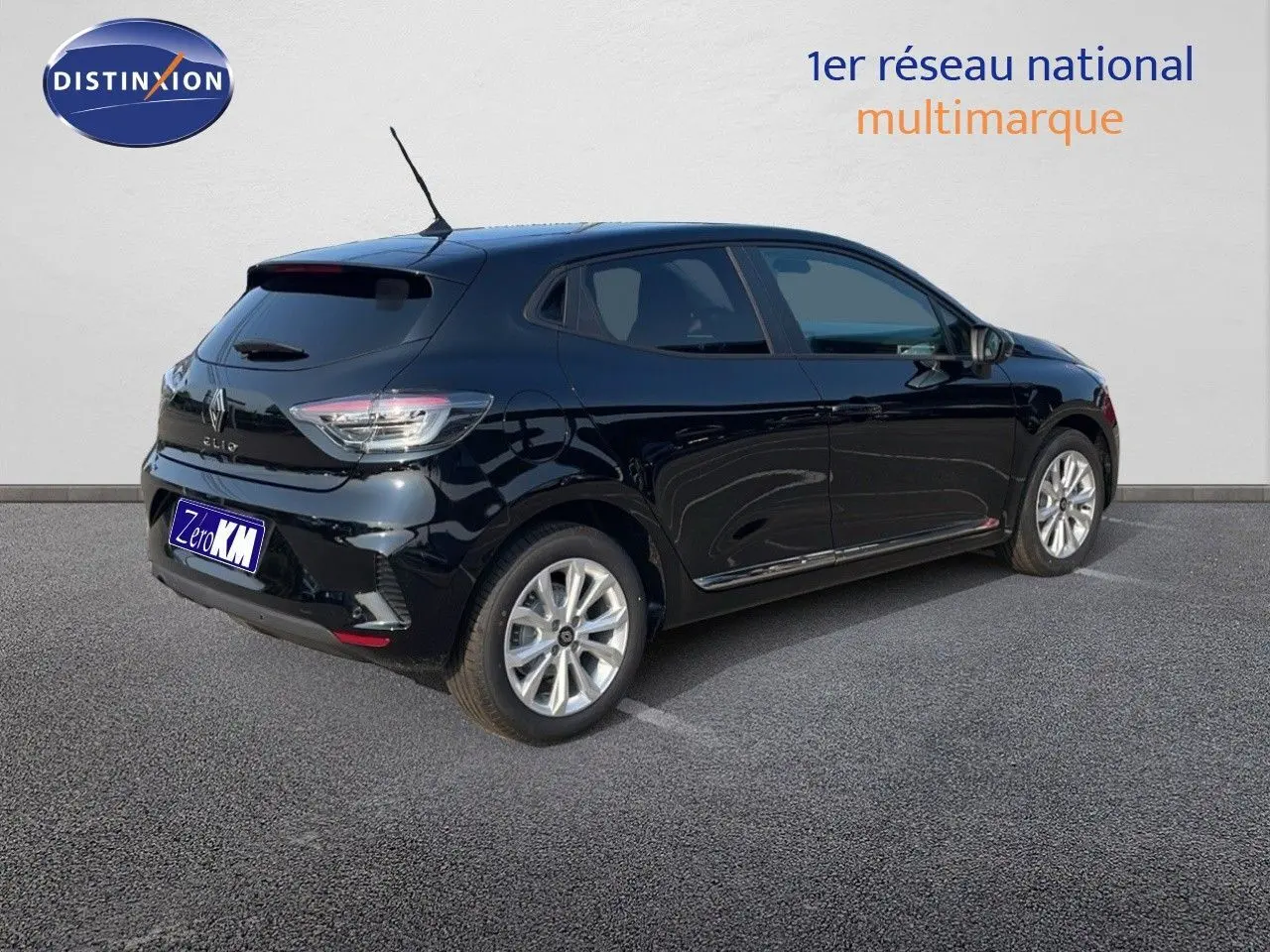 Renault Clio 2025 noir étoile métal vue 3/4 arrière côté droit sur parking devant mur blanc.