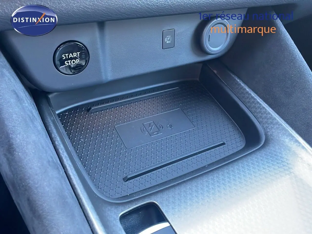 Gros plan sur la console centrale du Nissan Qashqai 2025 avec plateau de charge sans fil et bouton start/stop.