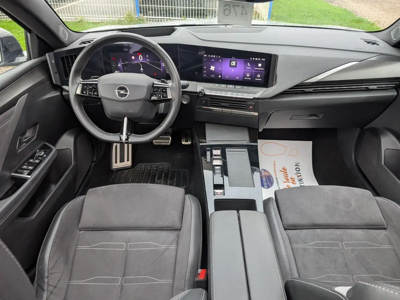 Intérieur avant d'une Opel Astra 2024, sellerie mixte noire, volant cuir, tableau de bord digital et écran tactile central.