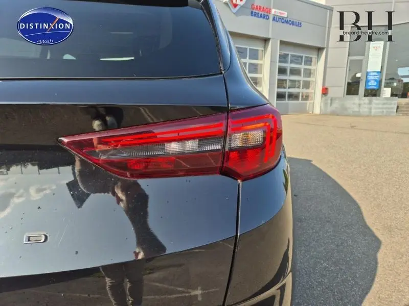 Gros plan sur le feu arrière droit d’un Opel Grandland noir diamant métallisé, avec reflet et arrière-plan de garage.