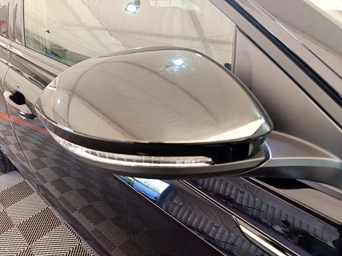 Gros plan sur le rétroviseur côté gauche noir brillant du Volkswagen Taigo 1.5 TSI 150 DSG R-Line 2023.