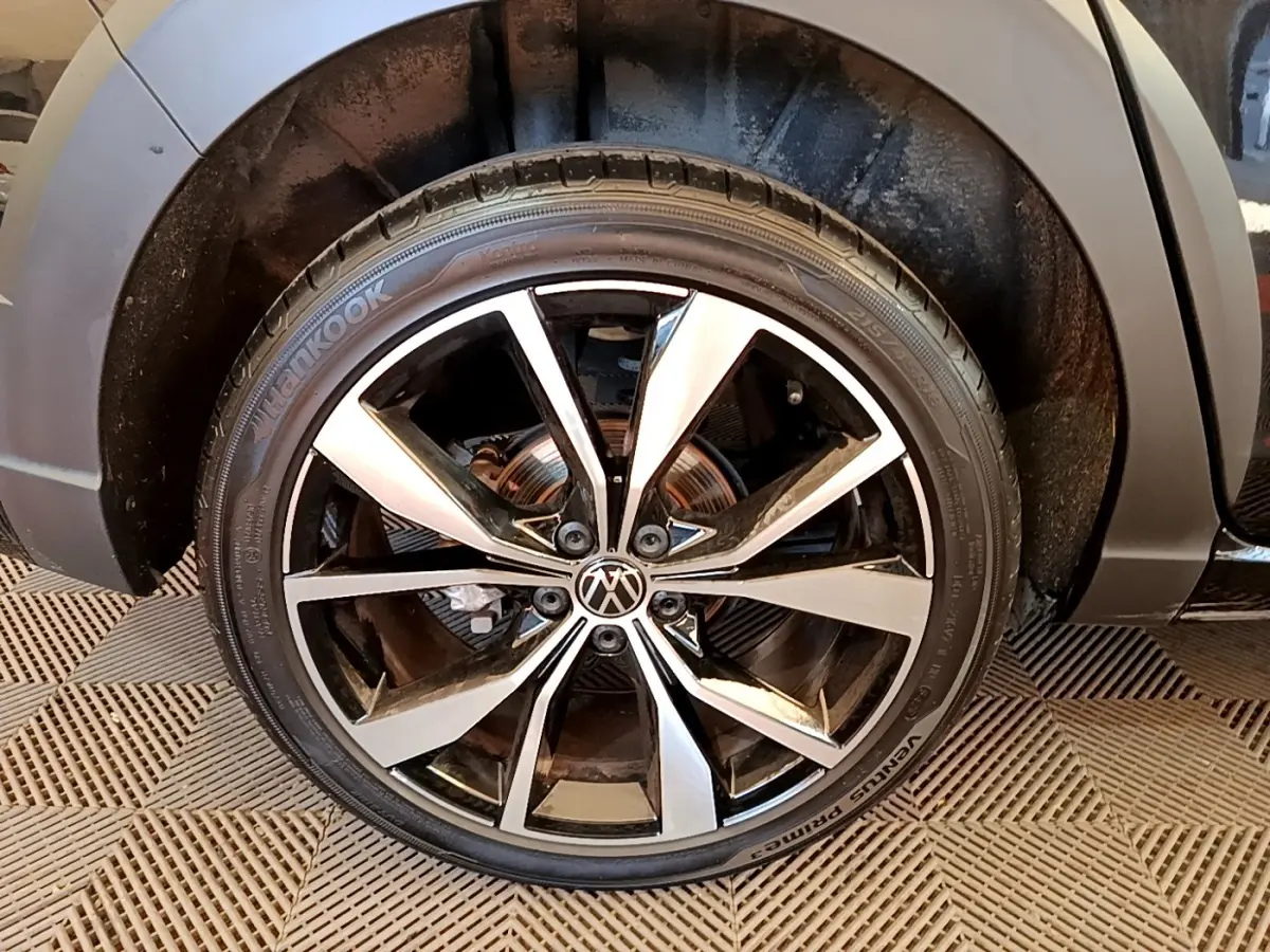 Gros plan sur la roue avant droite noire du Volkswagen Taigo 1.5 TSI 150 DSG R-Line avec jante alliage bicolore.