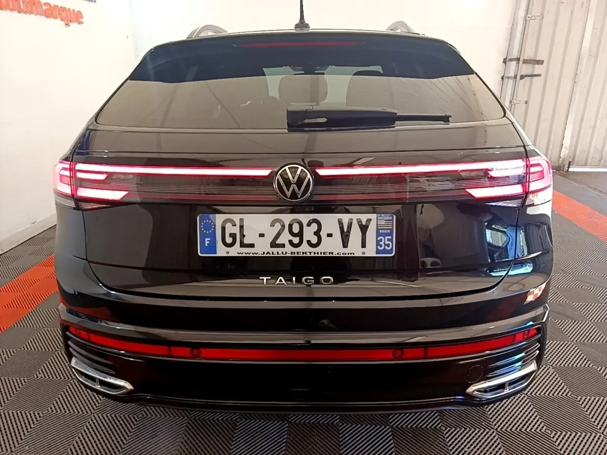 Vue arrière d’un Volkswagen Taigo noir 2023 avec feux LED allumés et double sortie d’échappement chromée.