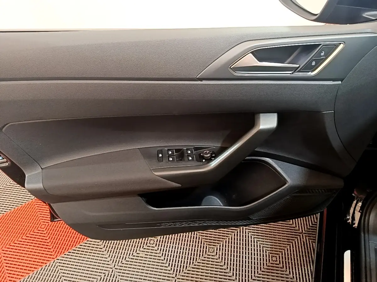 Vue côté gauche de la porte intérieure noire du Volkswagen Taigo 2023 avec commandes de vitres et verrouillage.