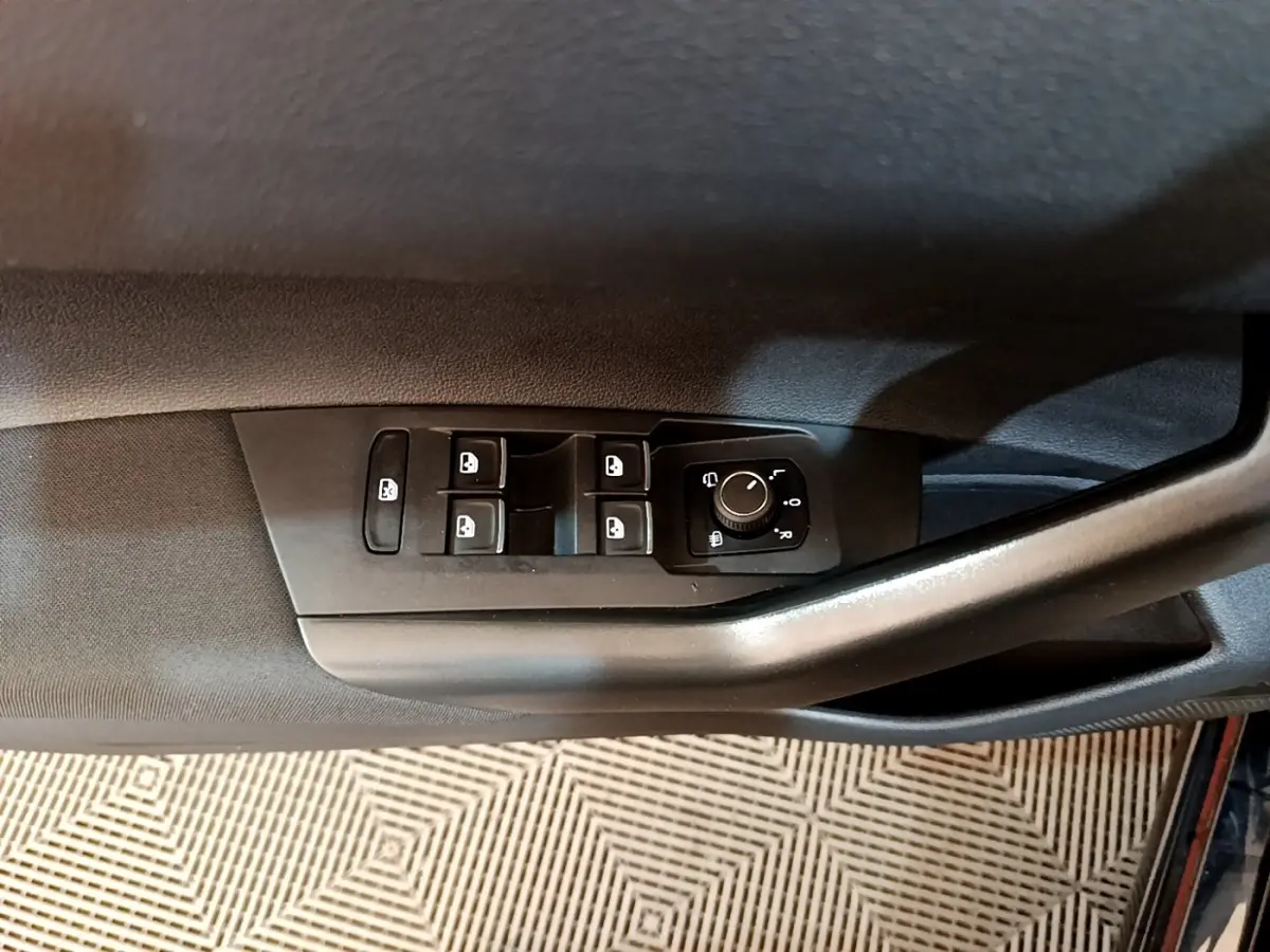 Vue rapprochée sur le panneau de commandes des vitres et rétroviseurs côté conducteur d’un Volkswagen Taigo noir 2023.