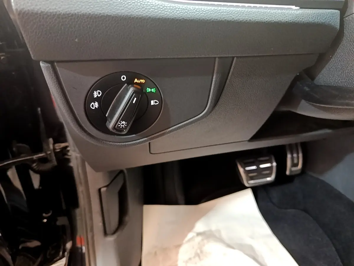 Détail du bouton de commande des phares sur le côté gauche du tableau de bord du Volkswagen Taigo noir 2023.