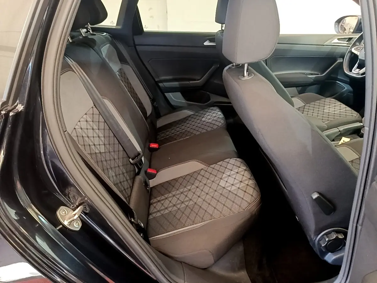 Vue intérieure côté gauche sur la banquette arrière et sièges avant du Volkswagen Taigo noir 2023 avec sellerie tissu à motifs.