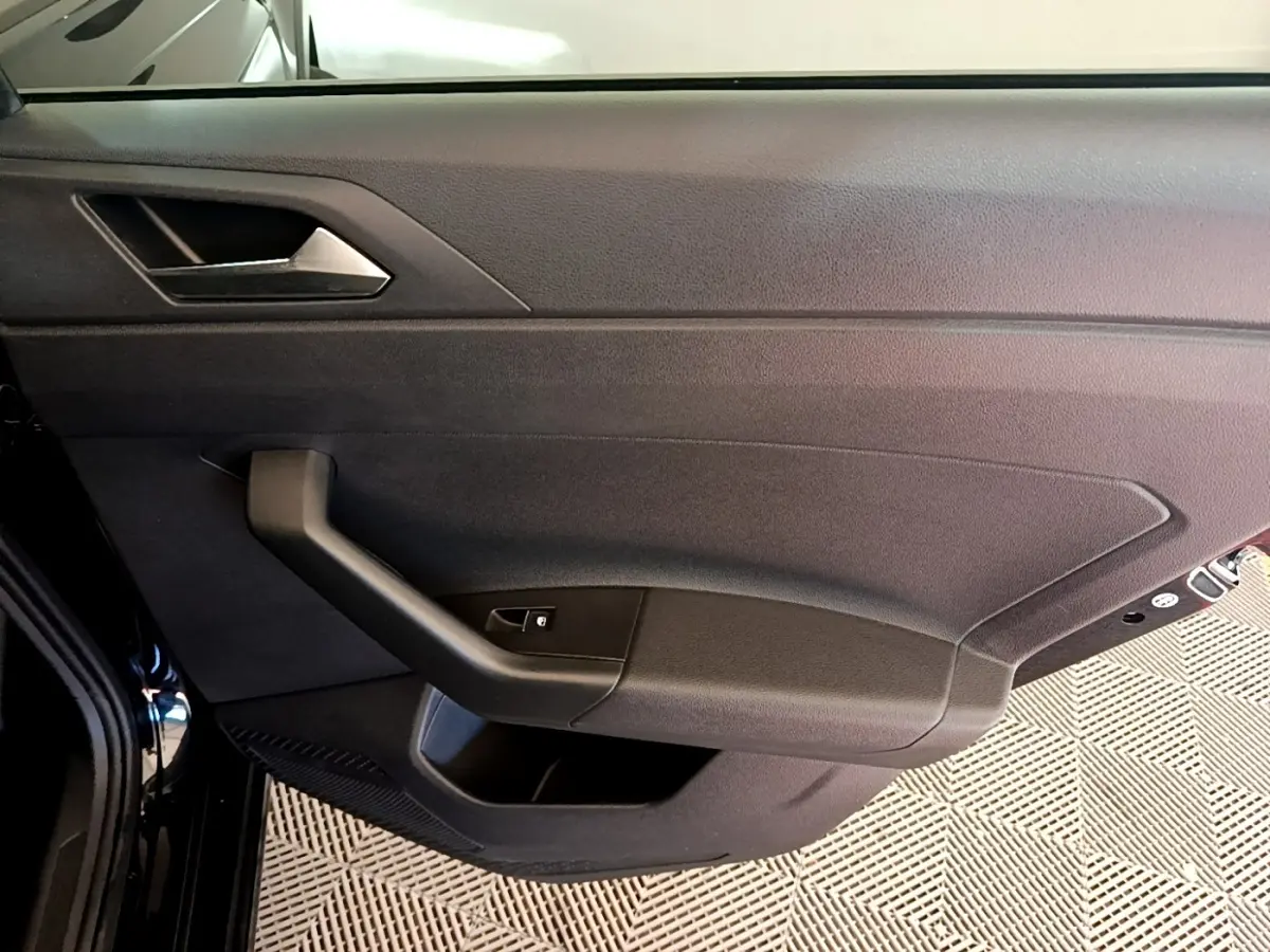 Vue intérieure de la porte côté gauche noire du Volkswagen Taigo 1.5 TSI 150 DSG R-Line avec poignée et commande de vitre.