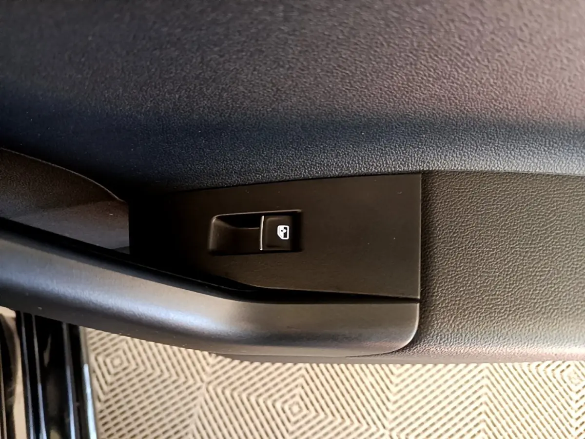Gros plan sur le bouton de verrouillage des portes côté conducteur d’un Volkswagen Taigo noir 2023.