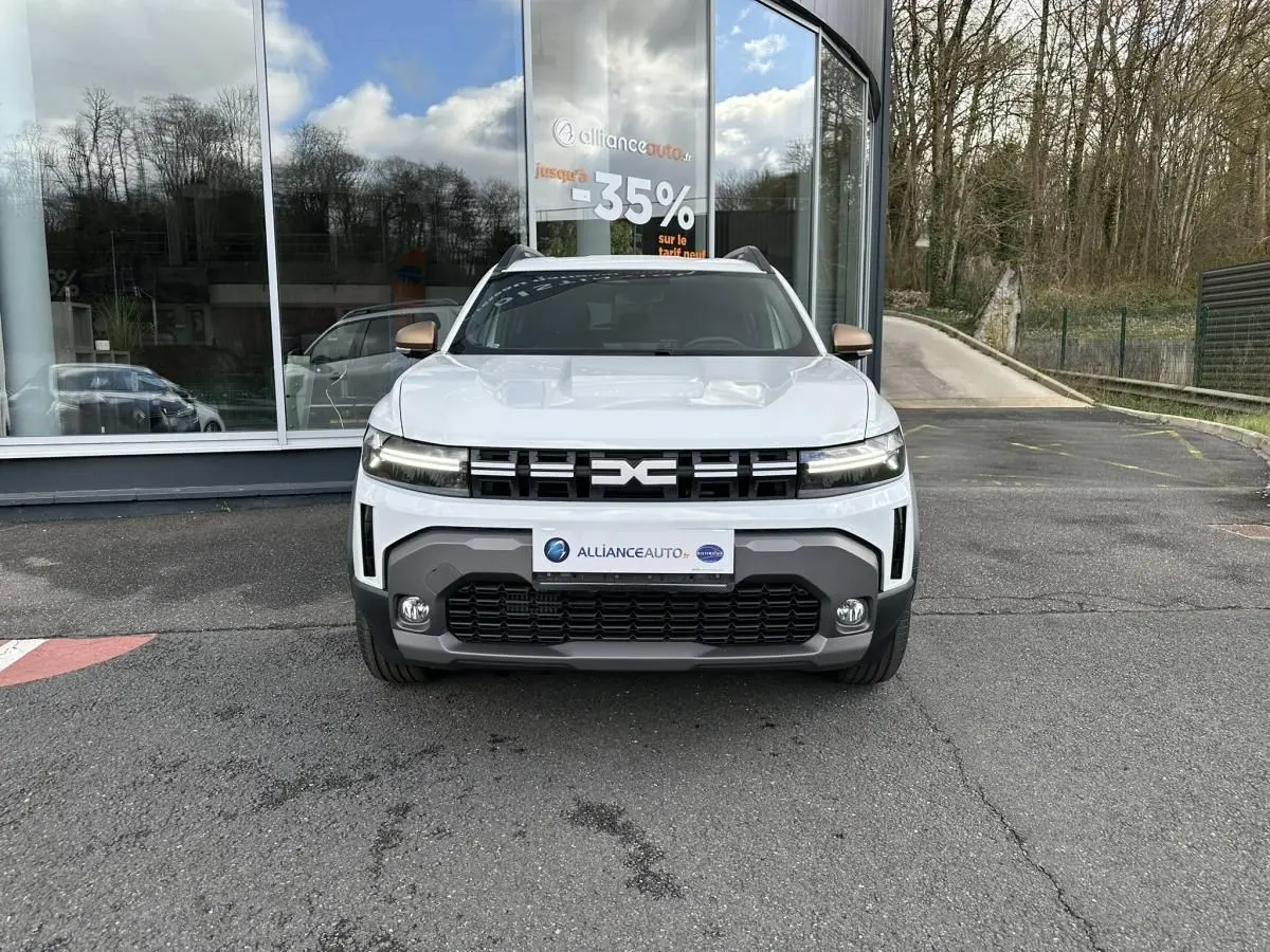 Vue avant du Dacia Duster blanc glacier 2025 avec calandre noire et projecteurs LED distinctifs.