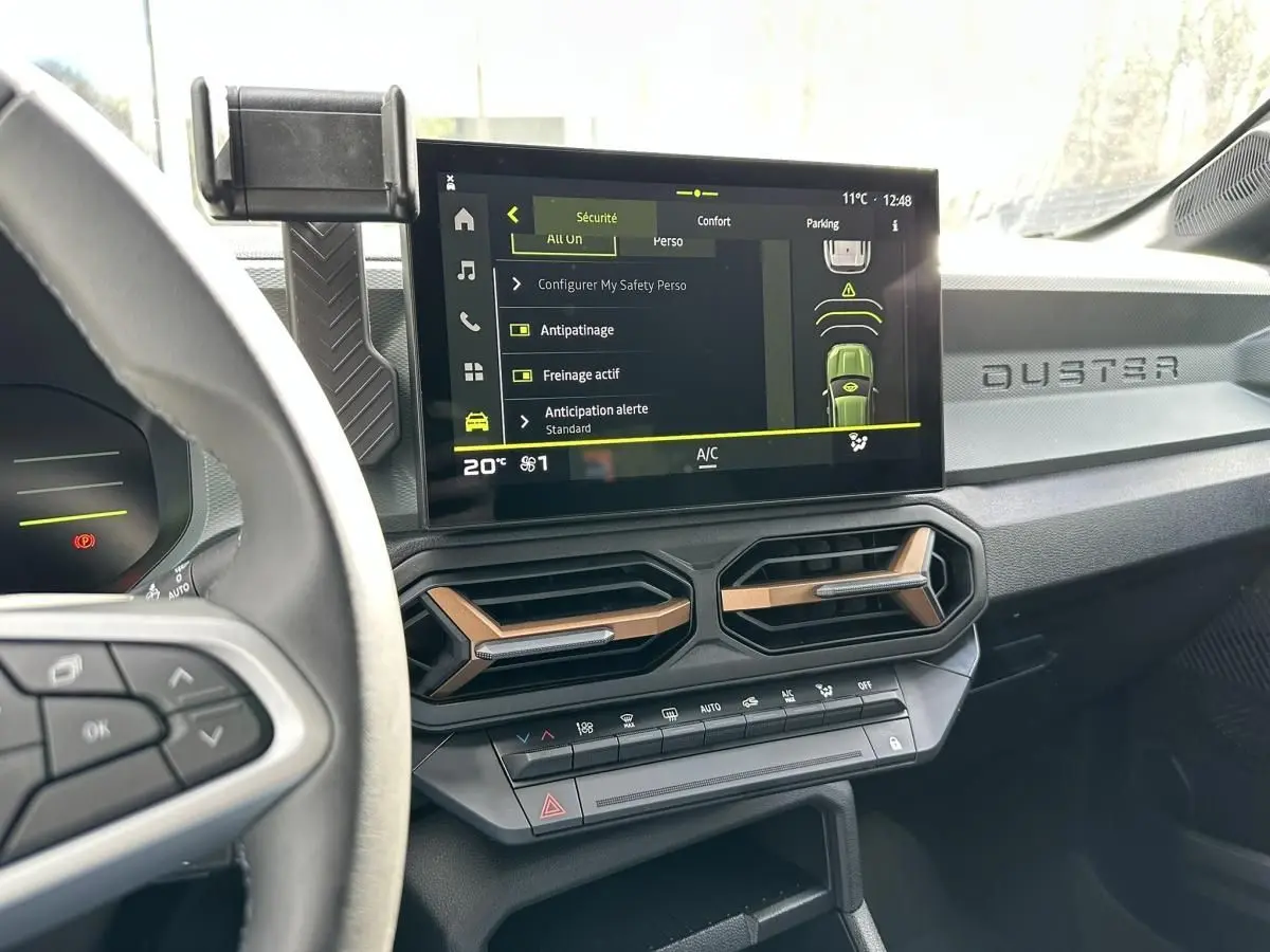 Vue intérieure du tableau de bord du Dacia Duster 2025, avec écran tactile central affichant les réglages de sécurité.
