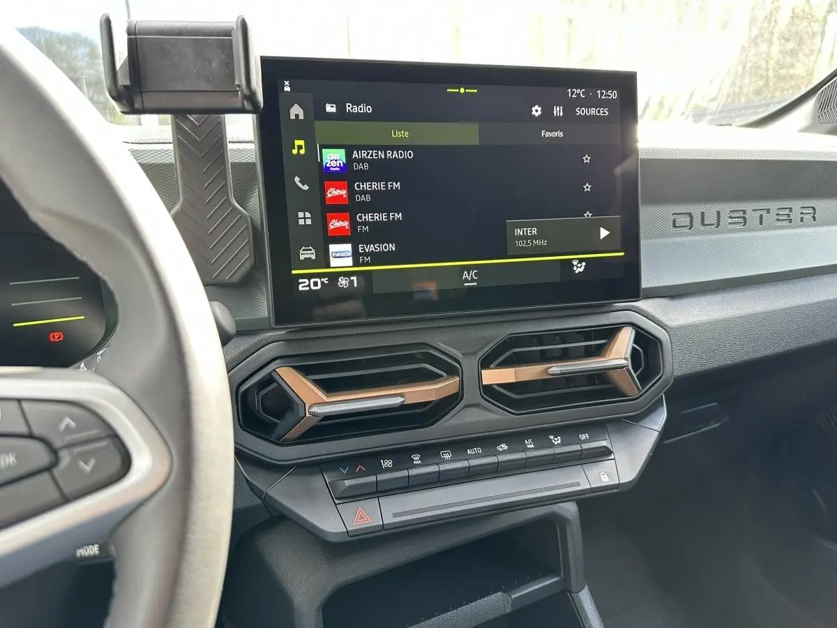 Vue intérieure du tableau de bord du Dacia Duster 2025, avec écran tactile central et aérateurs hexagonaux bronze.