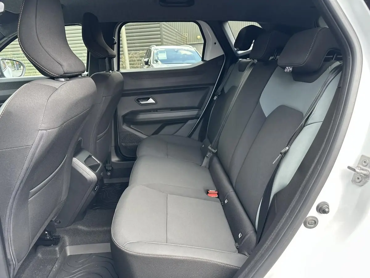 Vue intérieure côté droit sur la banquette arrière noire du Dacia Duster blanc glacier 2025, porte ouverte.