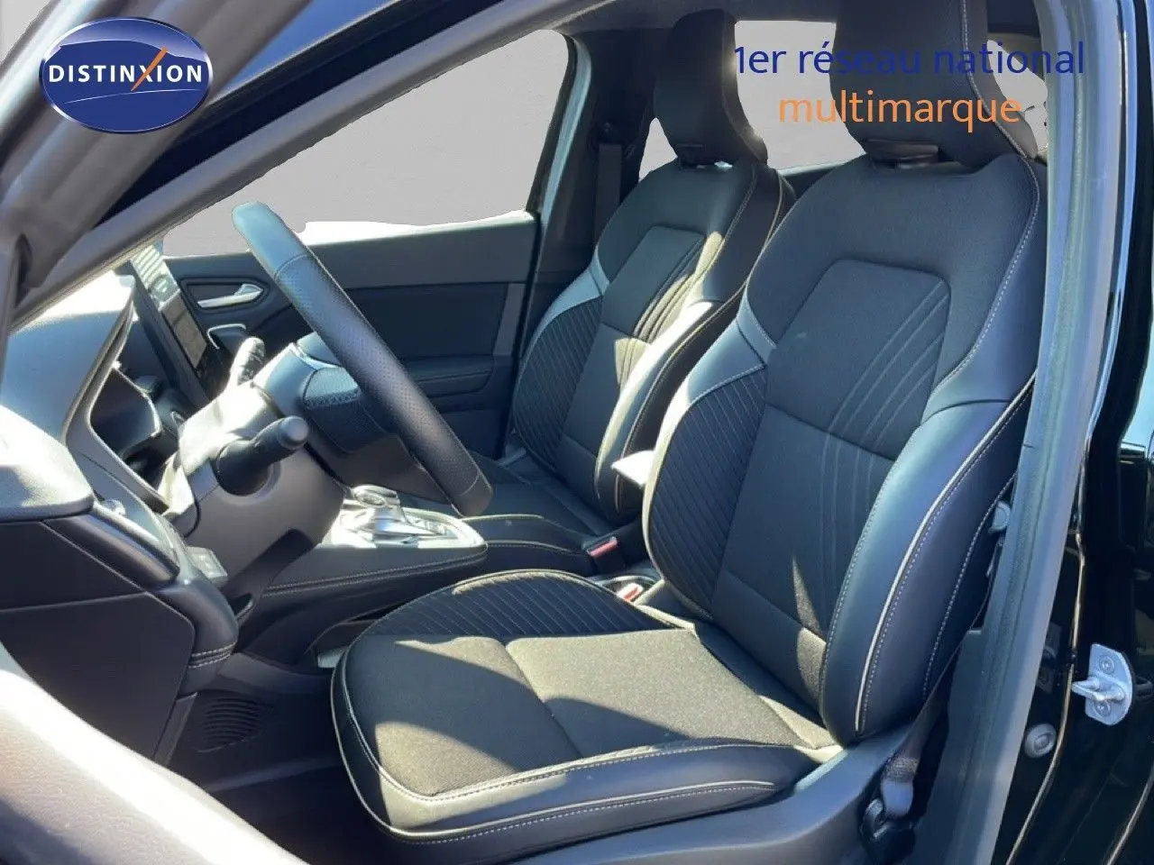 Vue intérieure côté conducteur de la Renault Symbioz noire étoile métal, mettant en valeur les sièges en tissu et cuir avec surpiqûres contrastées.
