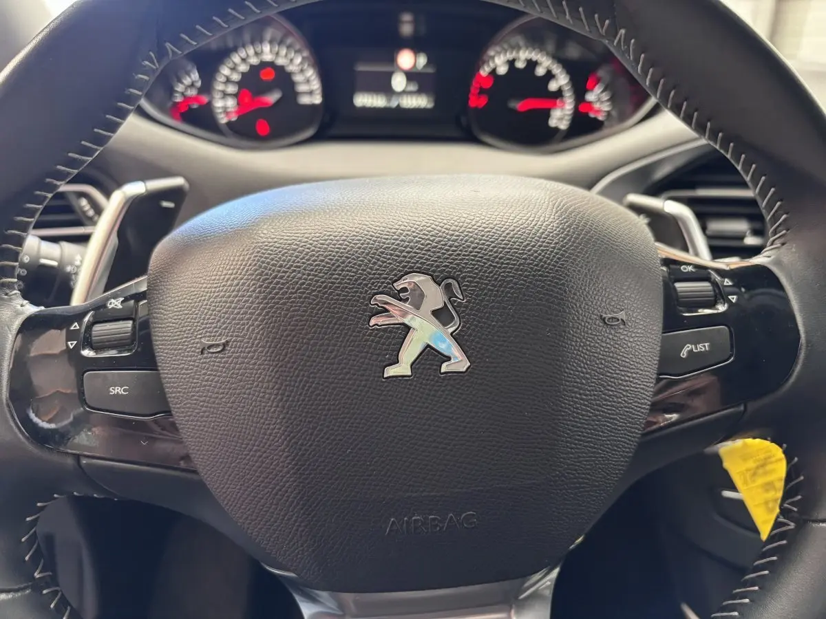 Volant en cuir noir de Peugeot 308 Puretech 2019 avec commandes intégrées et logo lion au centre, vue rapprochée frontale.