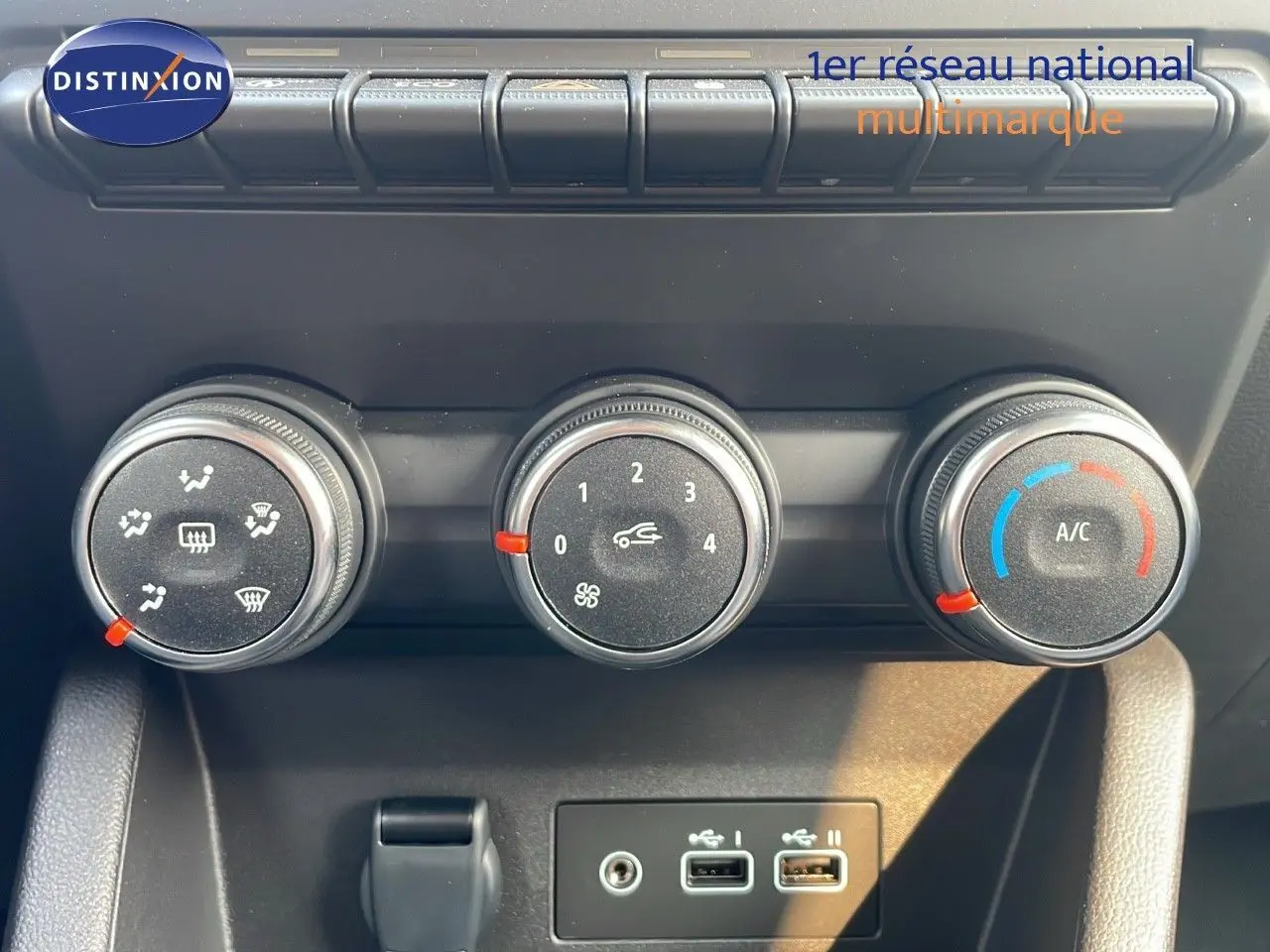 Gros plan sur les commandes de climatisation manuelle de la Renault Clio gris schiste, avec boutons de réglage et ports USB visibles.