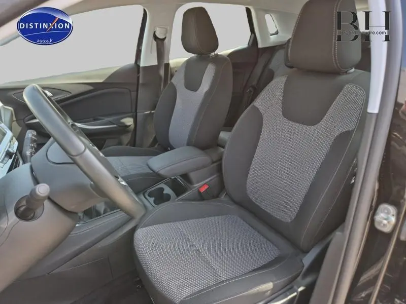 Intérieur avant de l'Opel Grandland 2023 noir Karbon, sièges tissu bicolore avec accoudoir central et volant cuir multifonction.