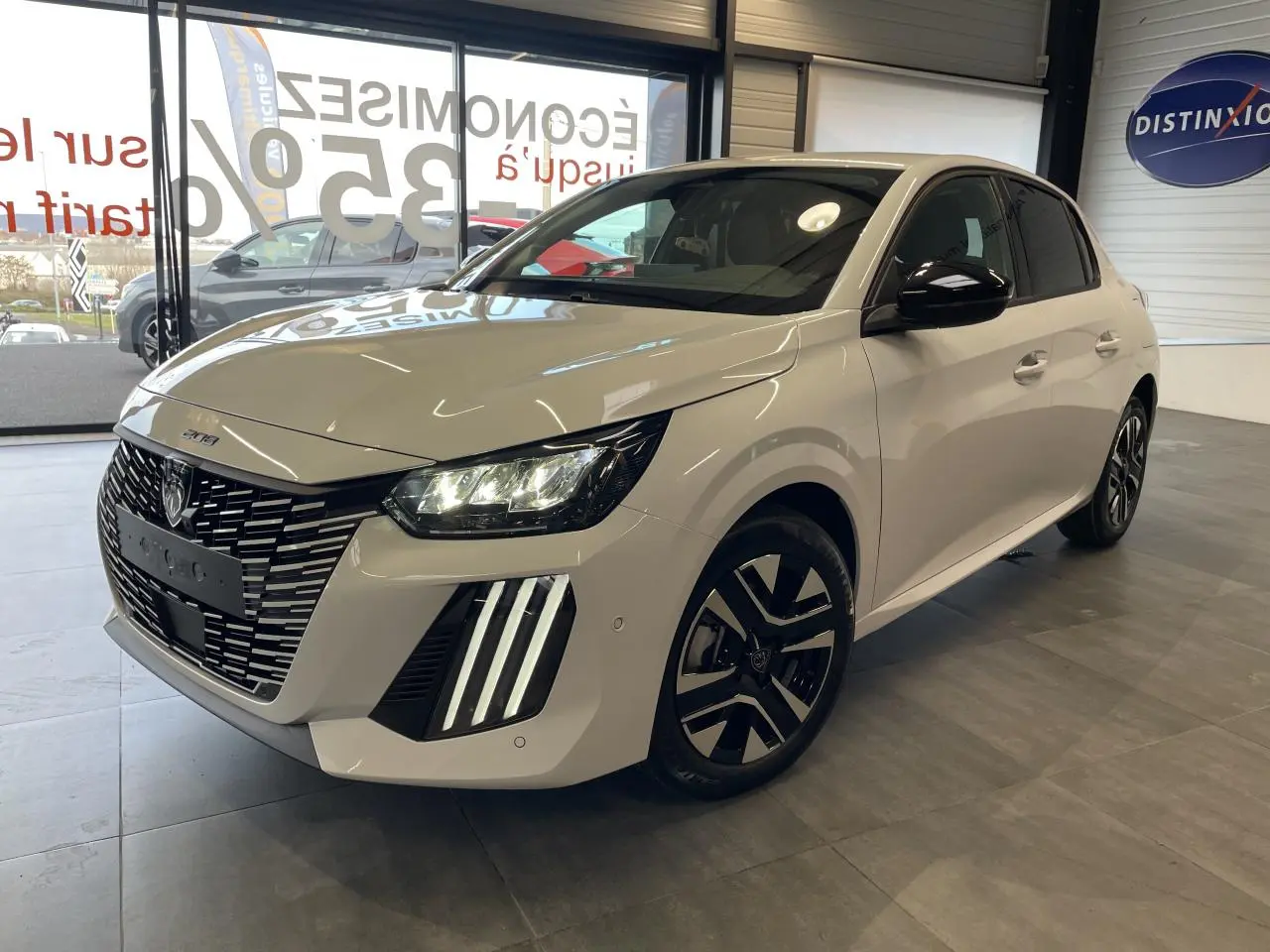 Peugeot 208 blanc okenite vue 3/4 avant droit, avec calandre noire et feux LED à signature verticale.