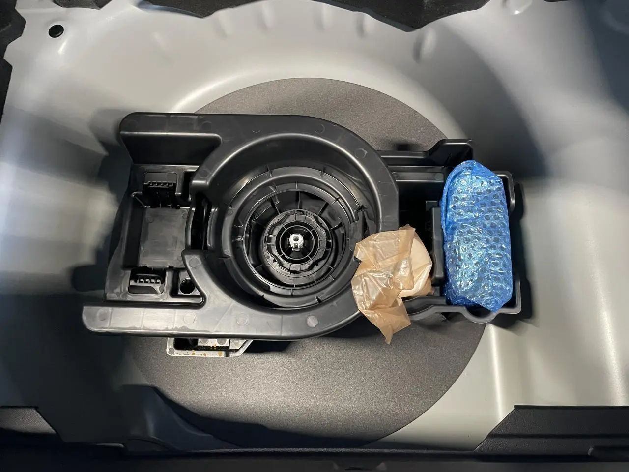 Vue plongeante sur le kit de dépannage pneumatique noir dans le coffre gris clair de la Peugeot 208 blanc okenite.