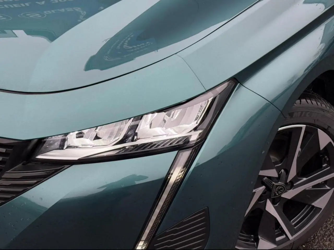 Gros plan sur l'avant droit bleu cuivre du Peugeot 308 SW Hybrid, mettant en valeur le phare LED et la jante alliage.
