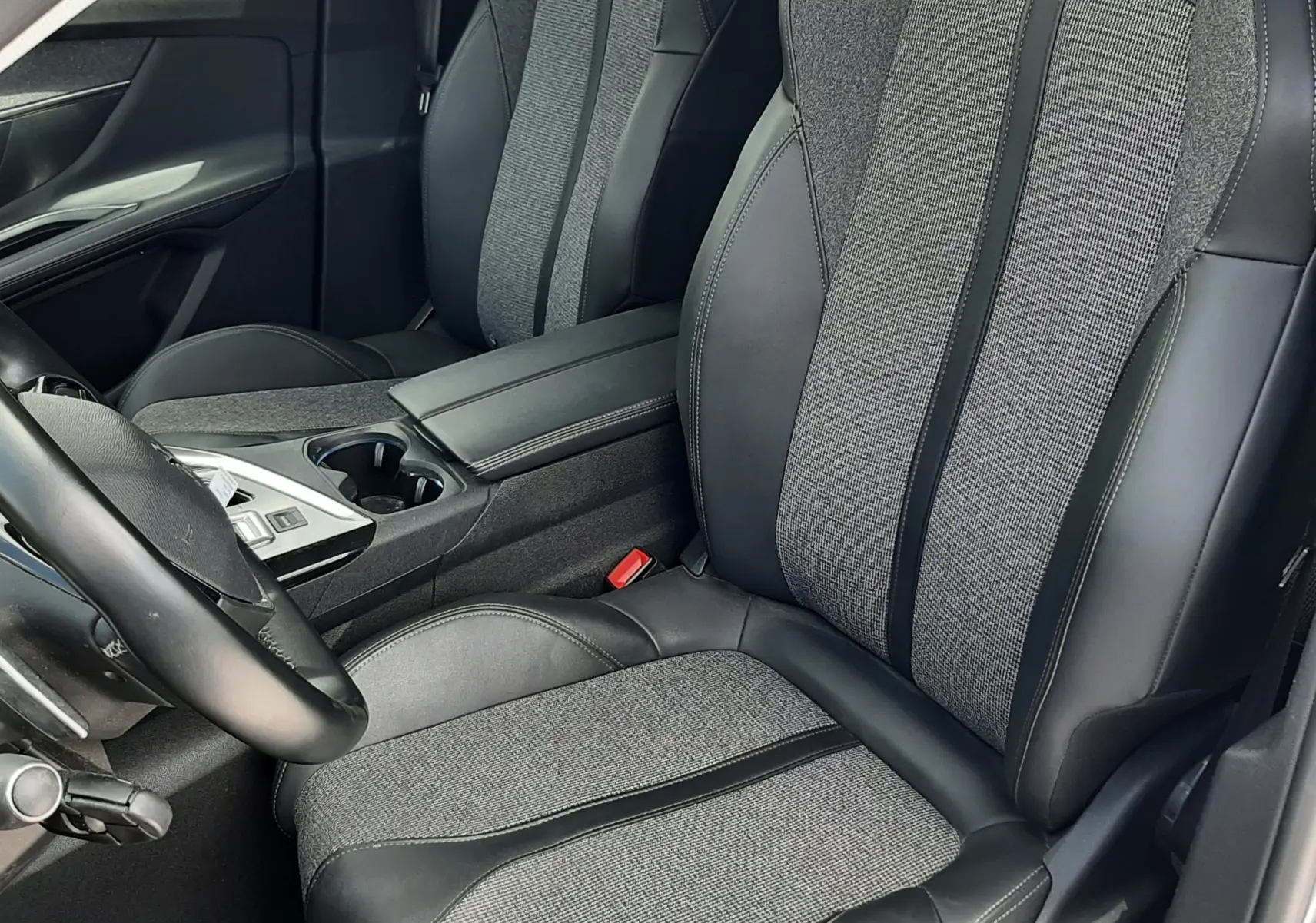 Vue intérieure rapprochée des sièges avant gris et noir en tissu et cuir du Peugeot 3008 2020 côté conducteur.