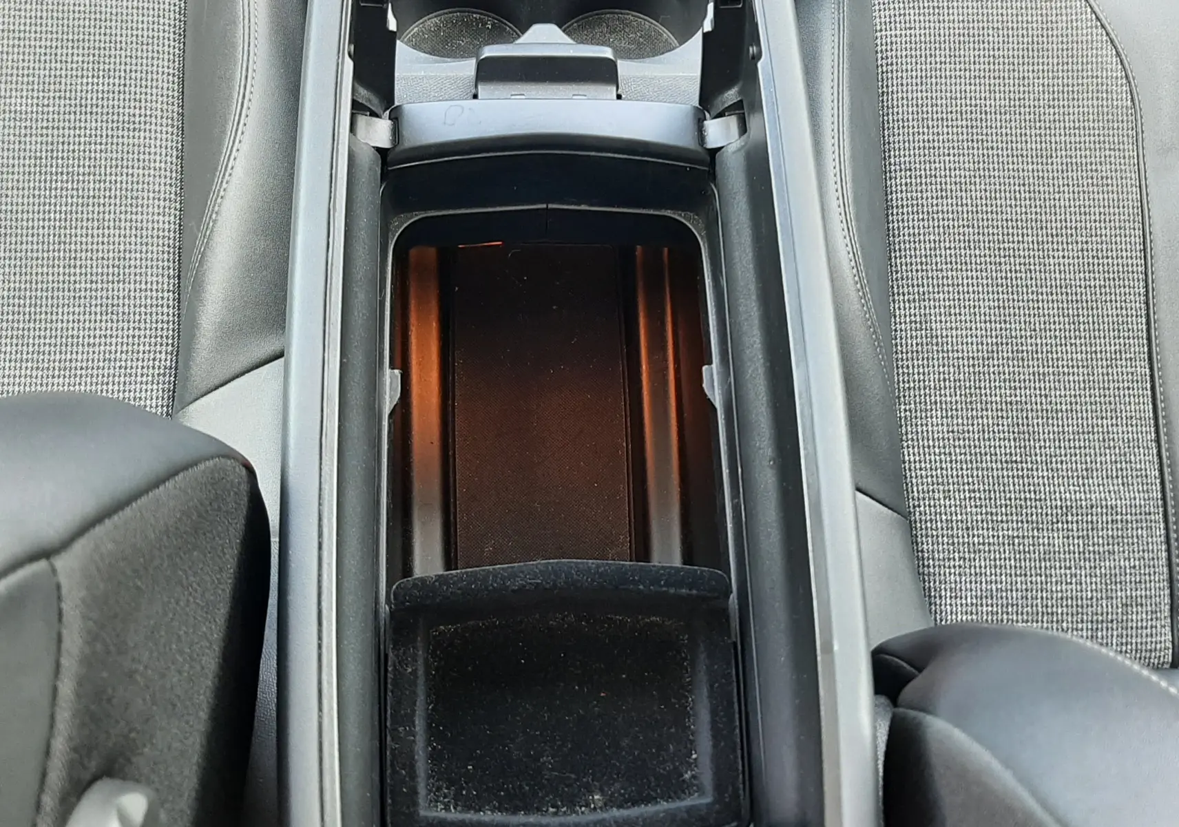 Vue plongeante sur la console centrale ouverte du Peugeot 3008 gris, montrant les porte-gobelets et le rangement intérieur.